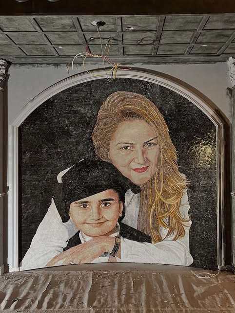 Large personal portrait mosaic set within an architectural arch during installation.